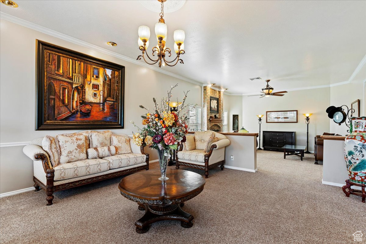 Carpeted living room featuring ceiling fan with notable chandelier and ornamental molding