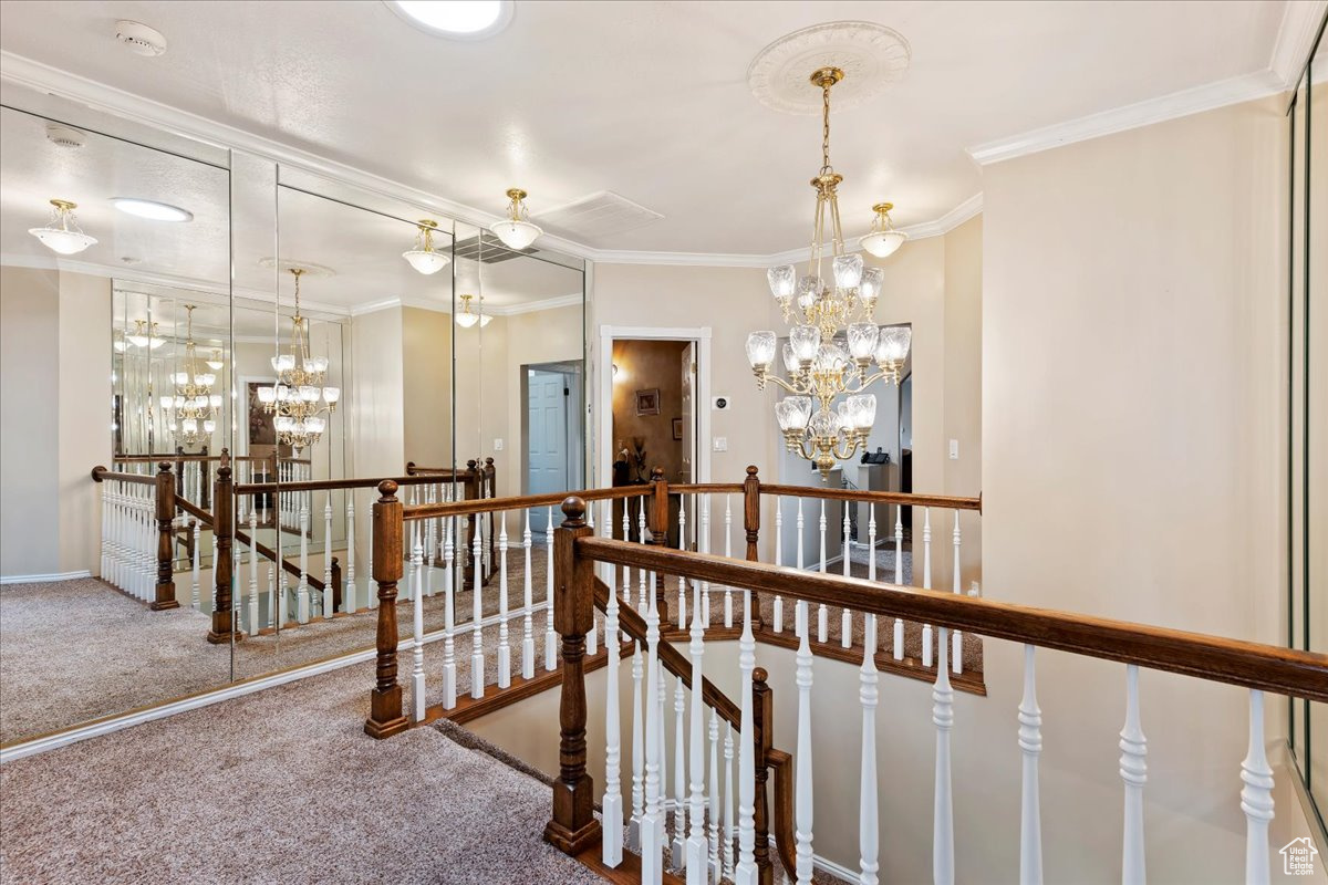 Hallway featuring carpet flooring, crown molding, and a chandelier