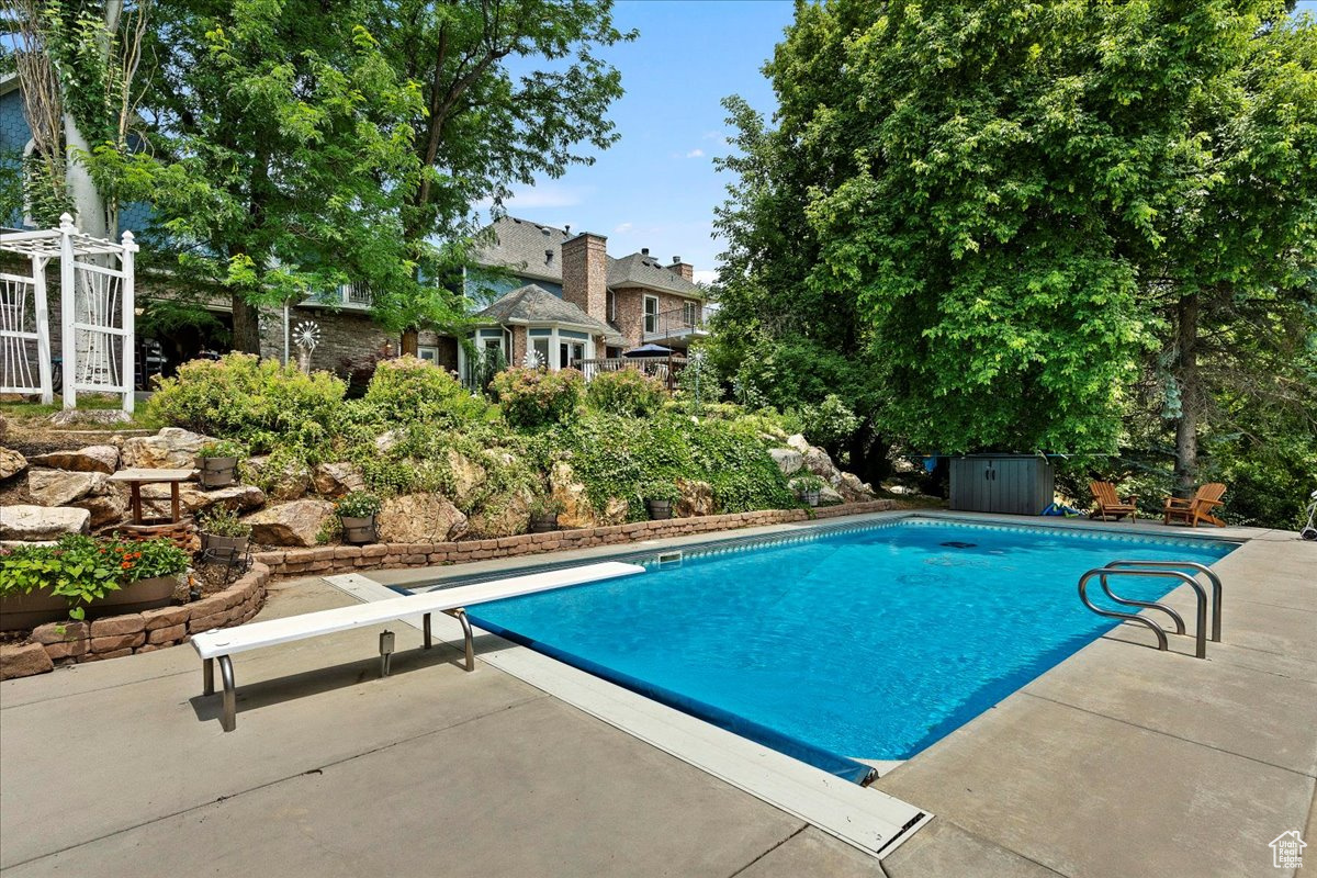 View of pool with a diving board and a patio area