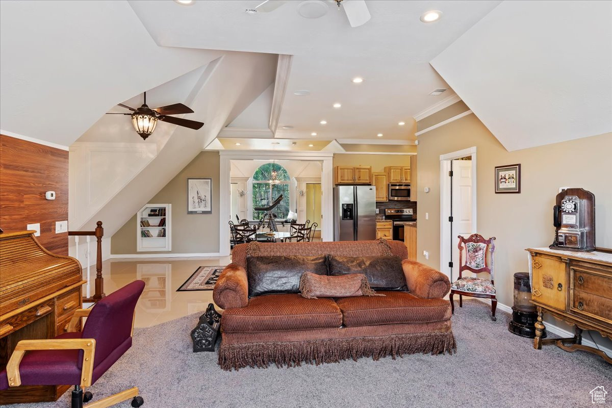 Carpeted living room with ceiling fan and crown molding