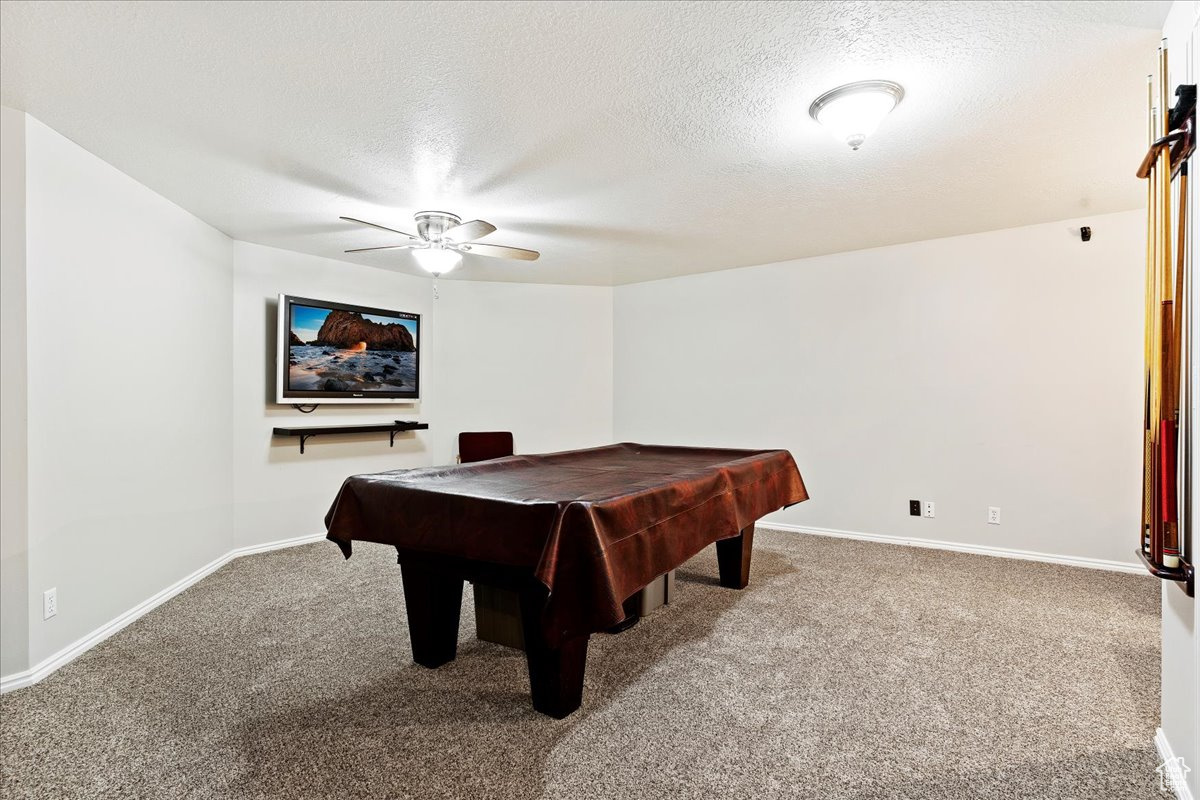 Recreation room with a textured ceiling, ceiling fan, carpet flooring, and pool table