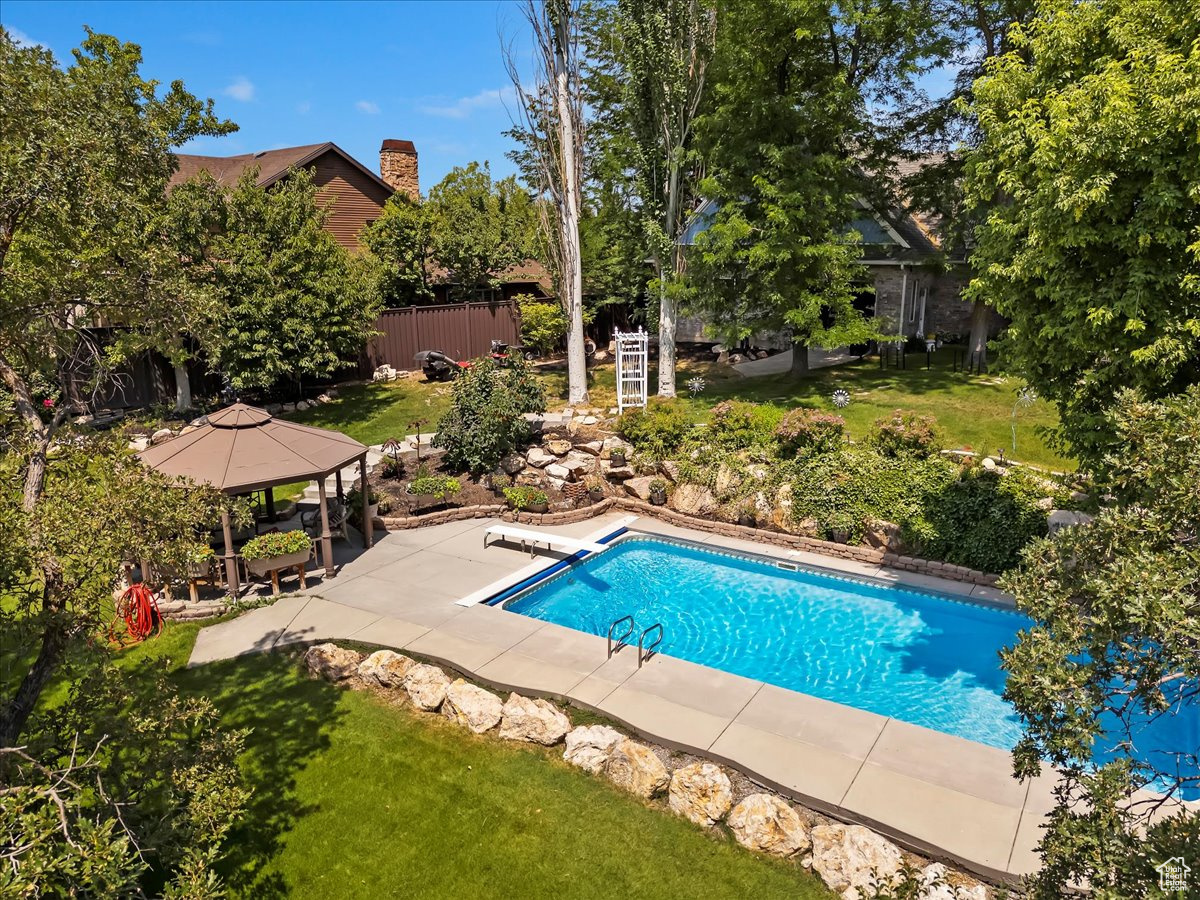 View of swimming pool with a patio, a gazebo, a yard, and a diving board