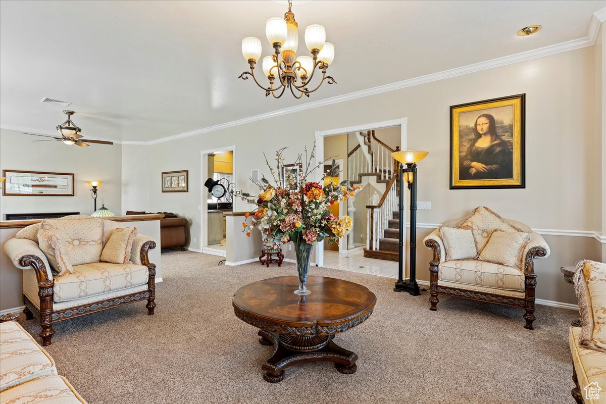 Carpeted living room featuring crown molding and a chandelier