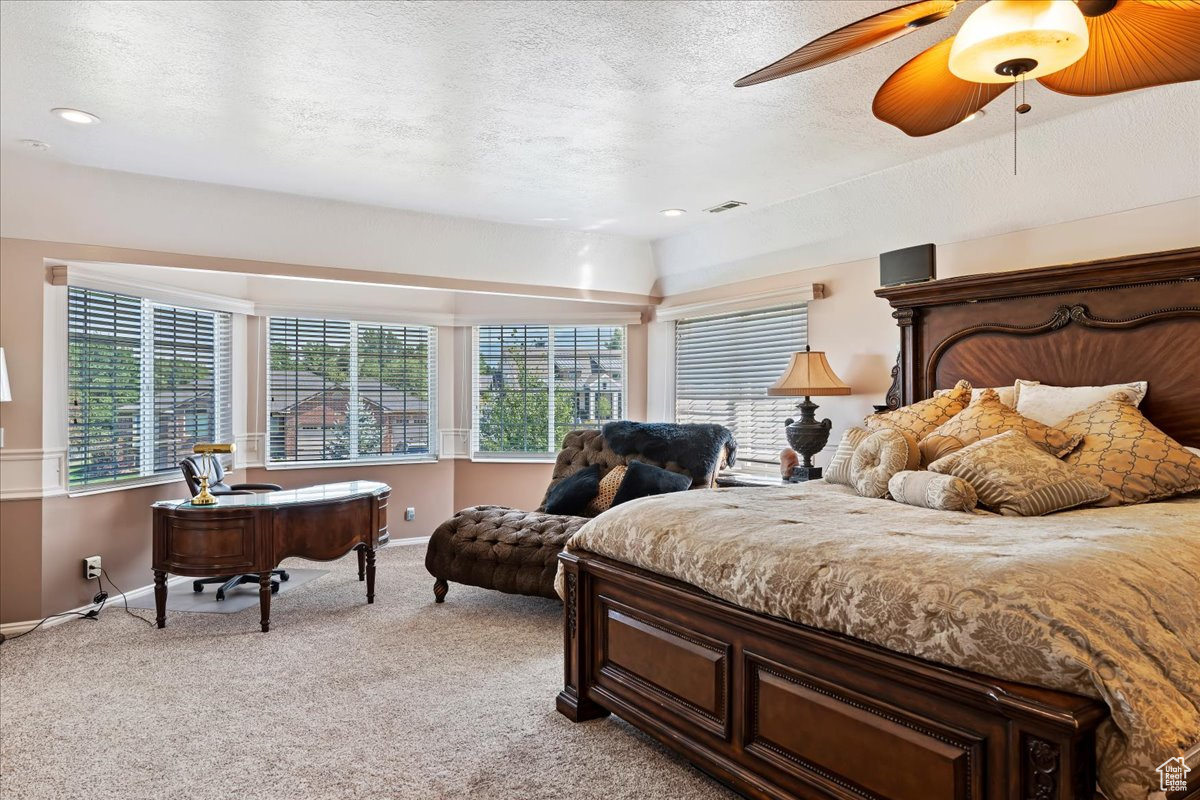 Bedroom with light carpet, a textured ceiling, and ceiling fan