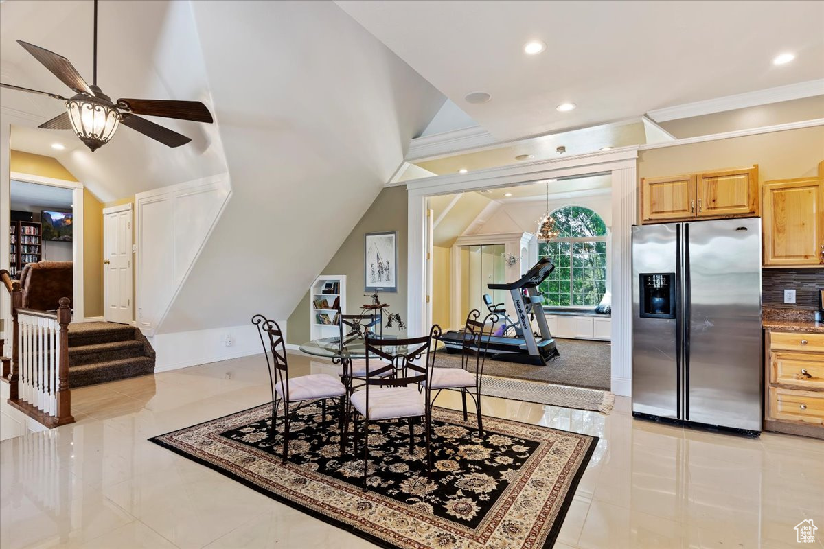 Dining area featuring light tile patterned flooring, ceiling fan, and vaulted ceiling