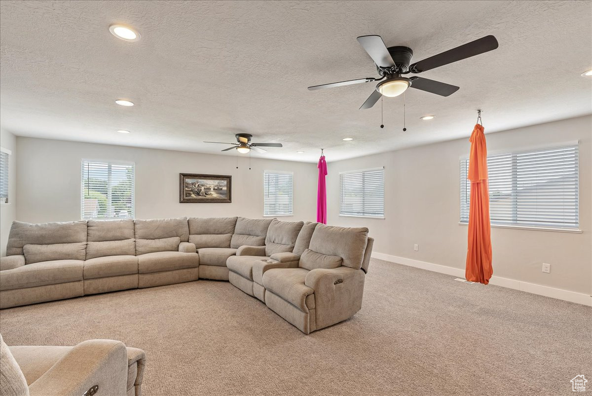 Carpeted living room with a textured ceiling and ceiling fan