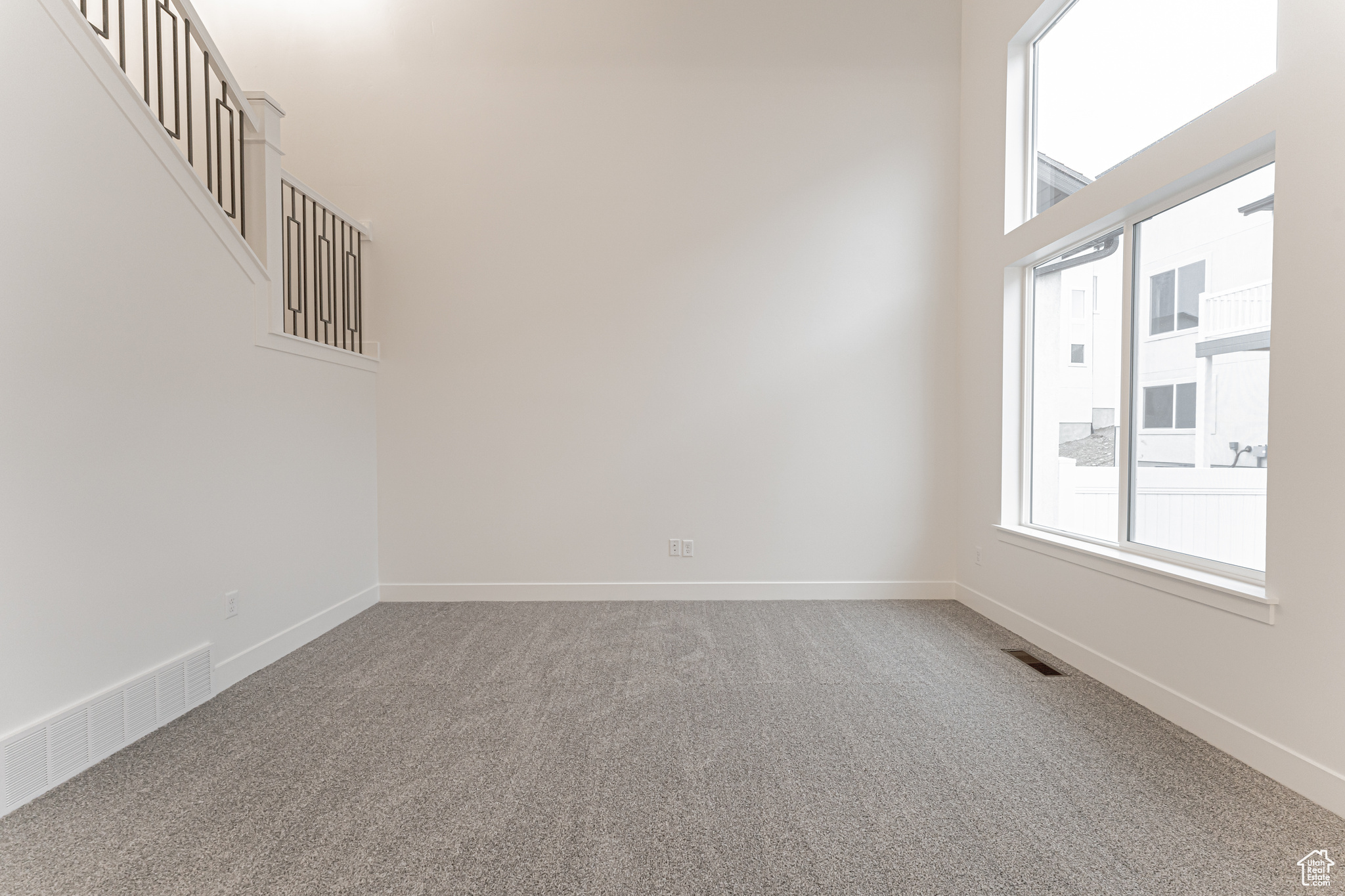 Carpeted spare room with a high ceiling