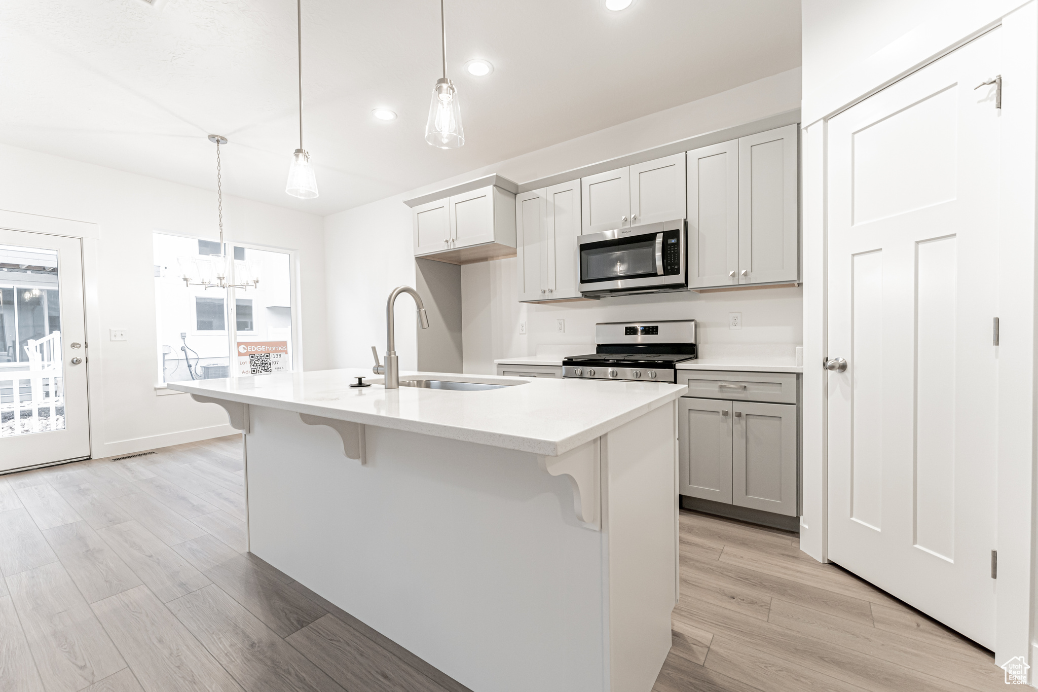 Kitchen featuring pendant lighting, sink, a kitchen island with sink, and appliances with stainless steel finishes