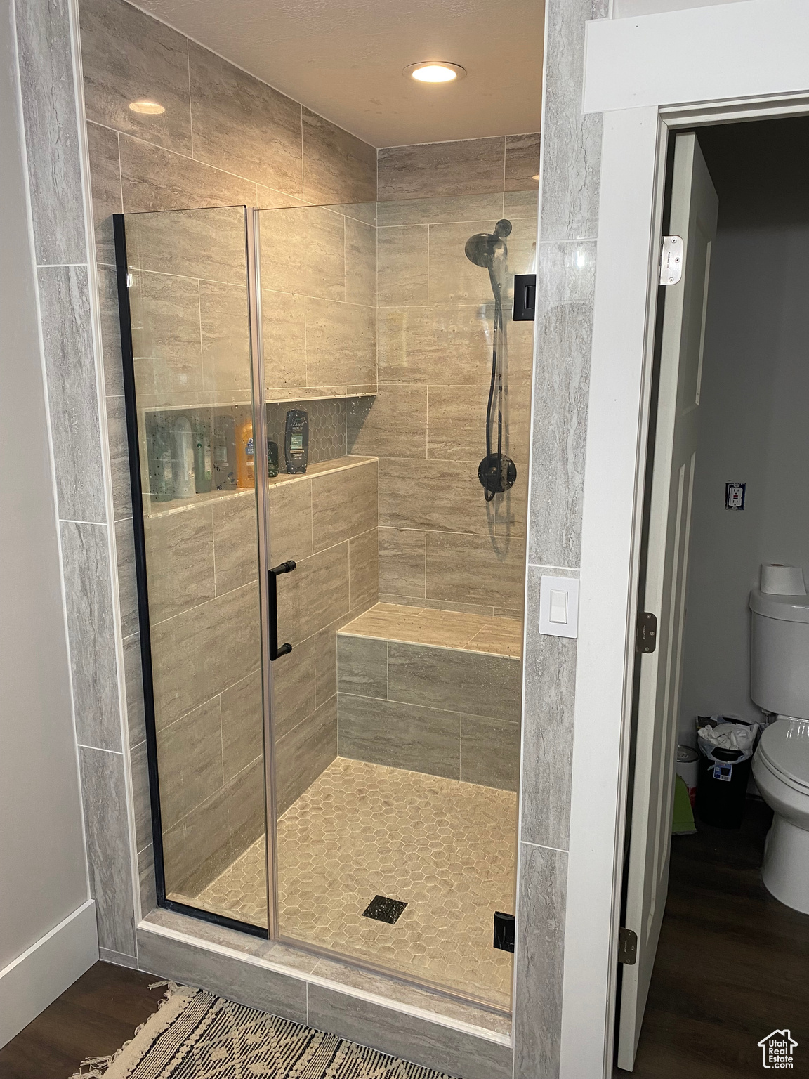 Bathroom with a shower with shower door, wood-type flooring, and toilet