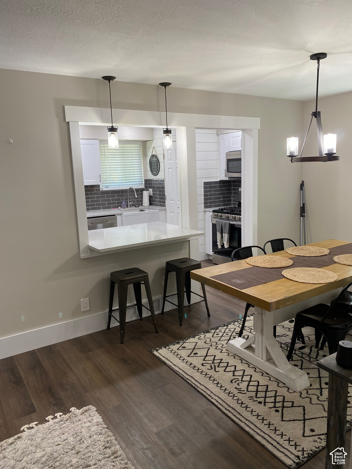 Dining space with sink, a textured ceiling, a chandelier, and dark wood-type flooring