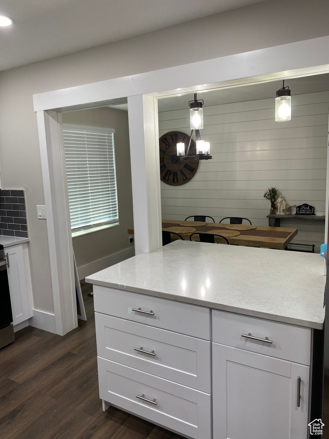 Kitchen with decorative light fixtures, white cabinets, dark hardwood / wood-style floors, and light stone countertops