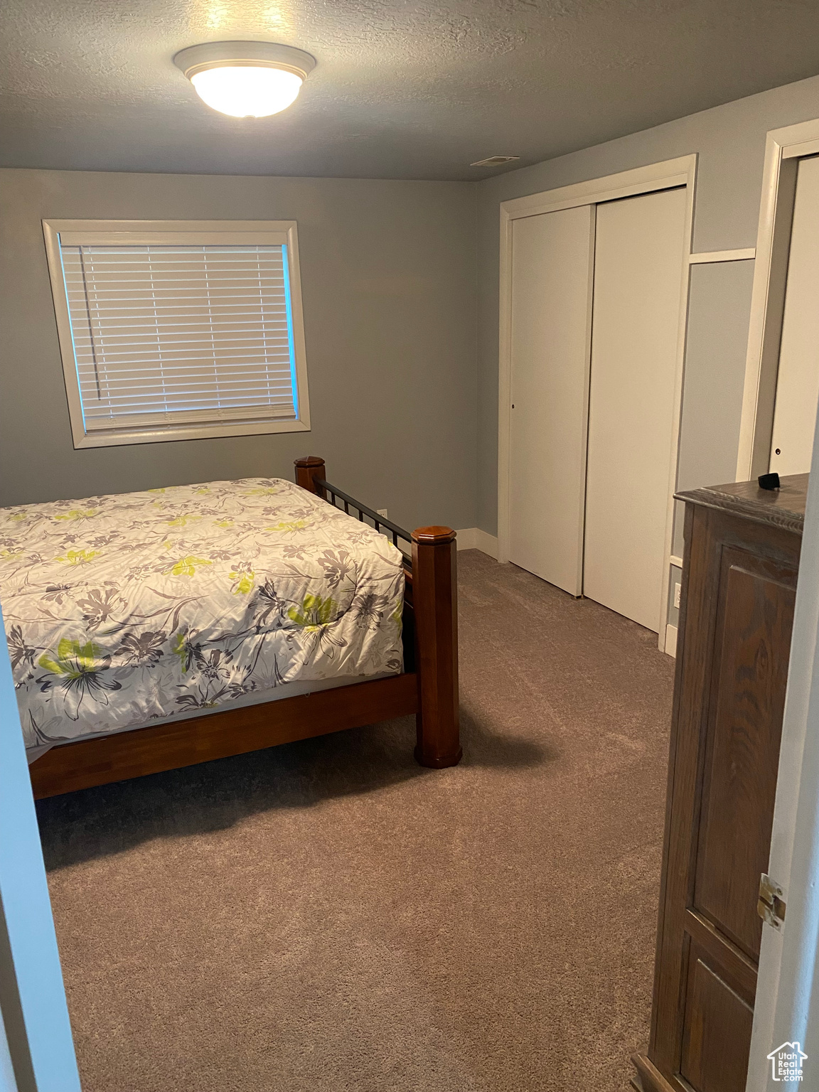 Bedroom with a closet, a textured ceiling, and dark carpet