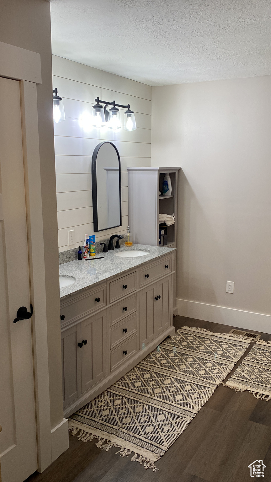 Bathroom with double vanity, a textured ceiling, and hardwood / wood-style floors