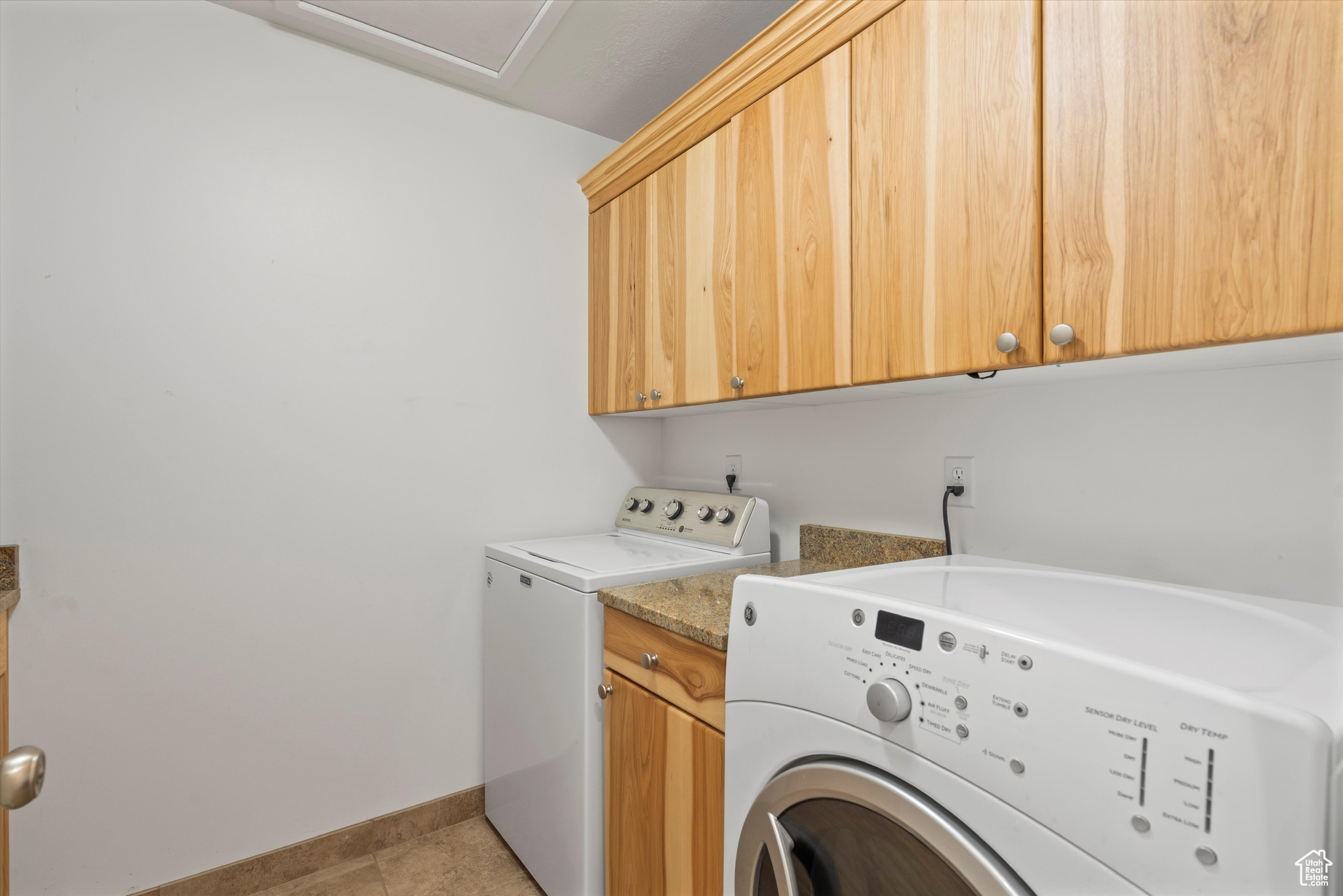 Laundry room with light tile patterned flooring, separate washer and dryer, and cabinets