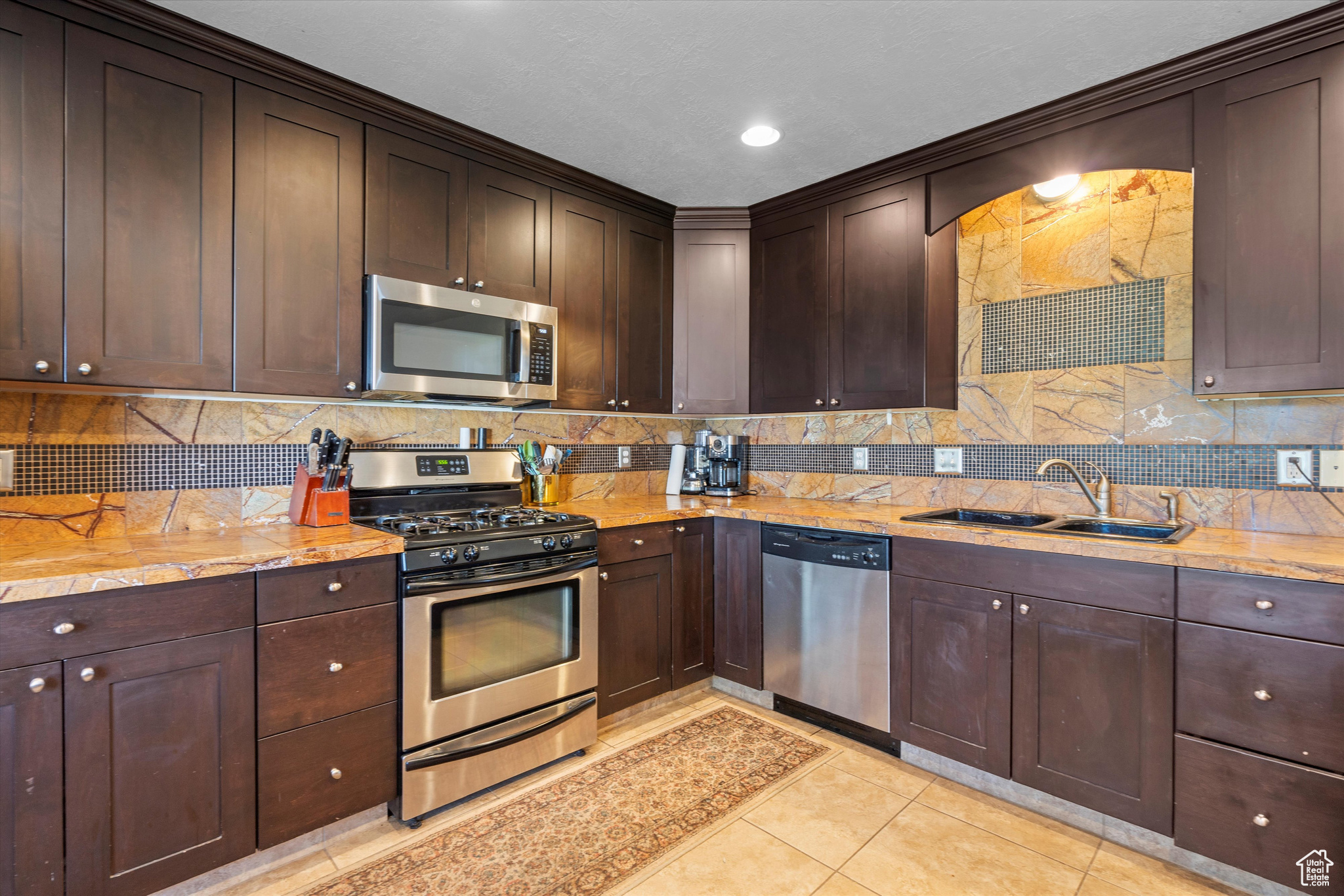 2nd Kitchen with light tile patterned flooring, decorative backsplash, appliances with stainless steel finishes.