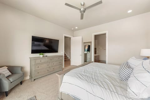 Carpeted bedroom featuring ensuite bathroom and ceiling fan