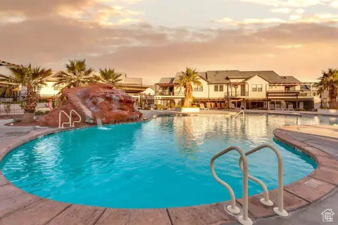 Pool at dusk featuring pool water feature