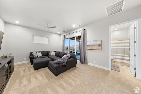 Carpeted living room featuring ceiling fan