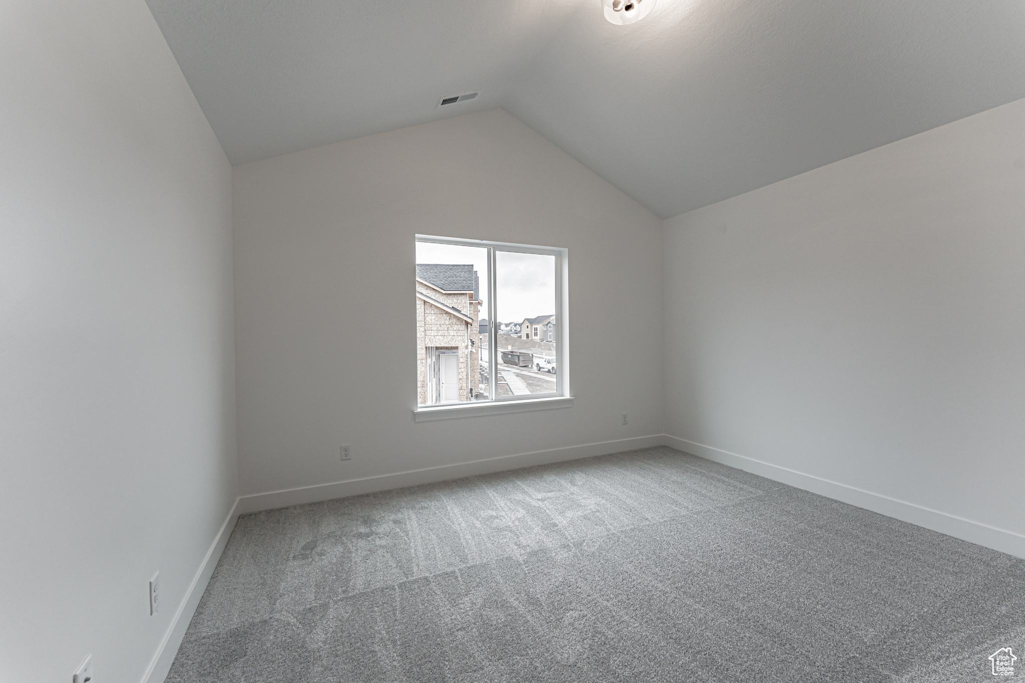 Spare room featuring carpet flooring and lofted ceiling