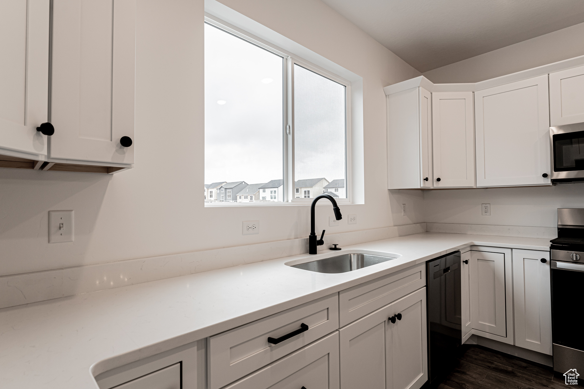 Kitchen featuring white cabinets, appliances with stainless steel finishes, dark hardwood / wood-style floors, and sink