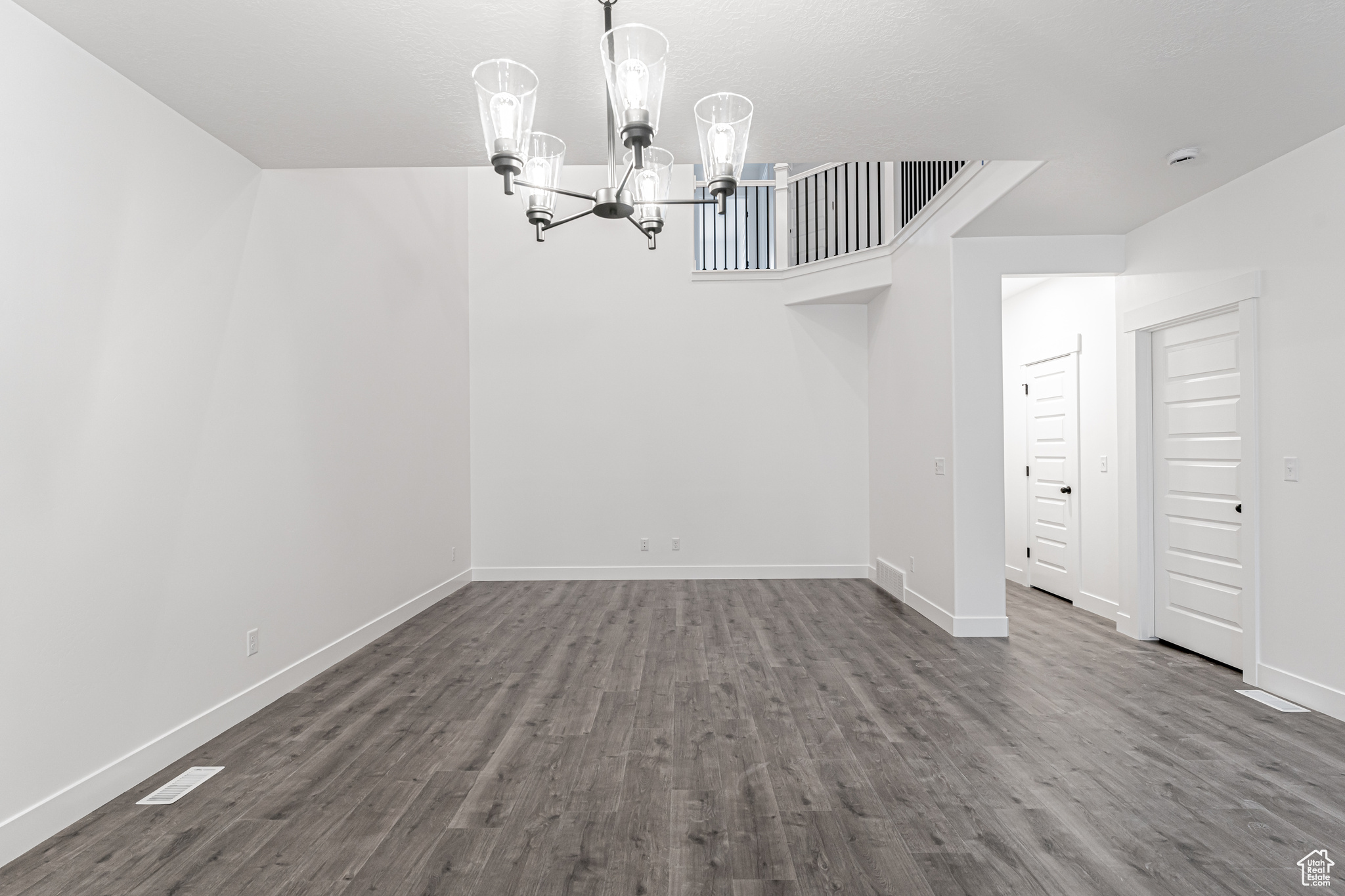 Unfurnished dining area with dark wood-type flooring and an inviting chandelier