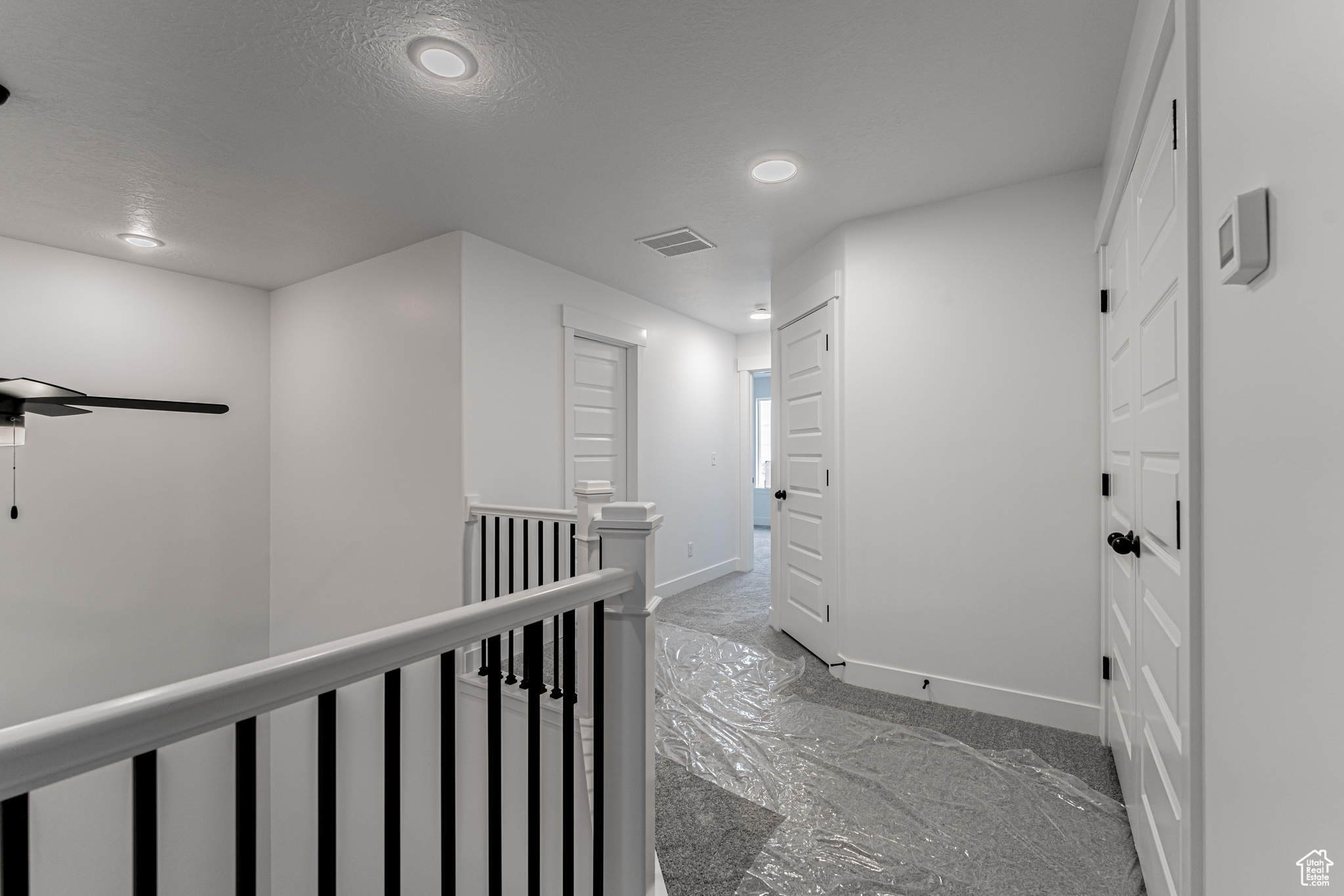 Hallway with dark colored carpet and a textured ceiling