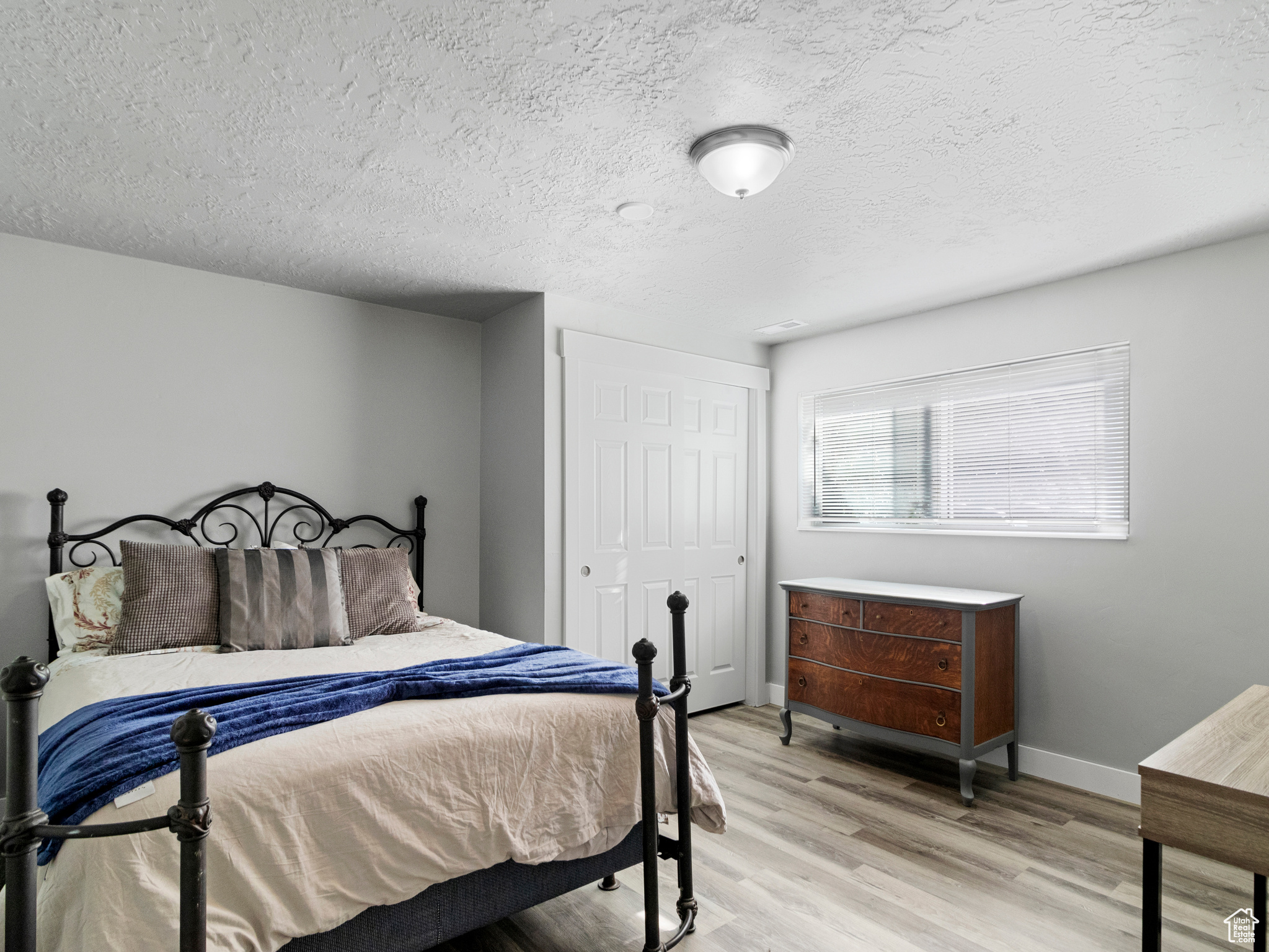 Bedroom with light hardwood / wood-style floors and a textured ceiling