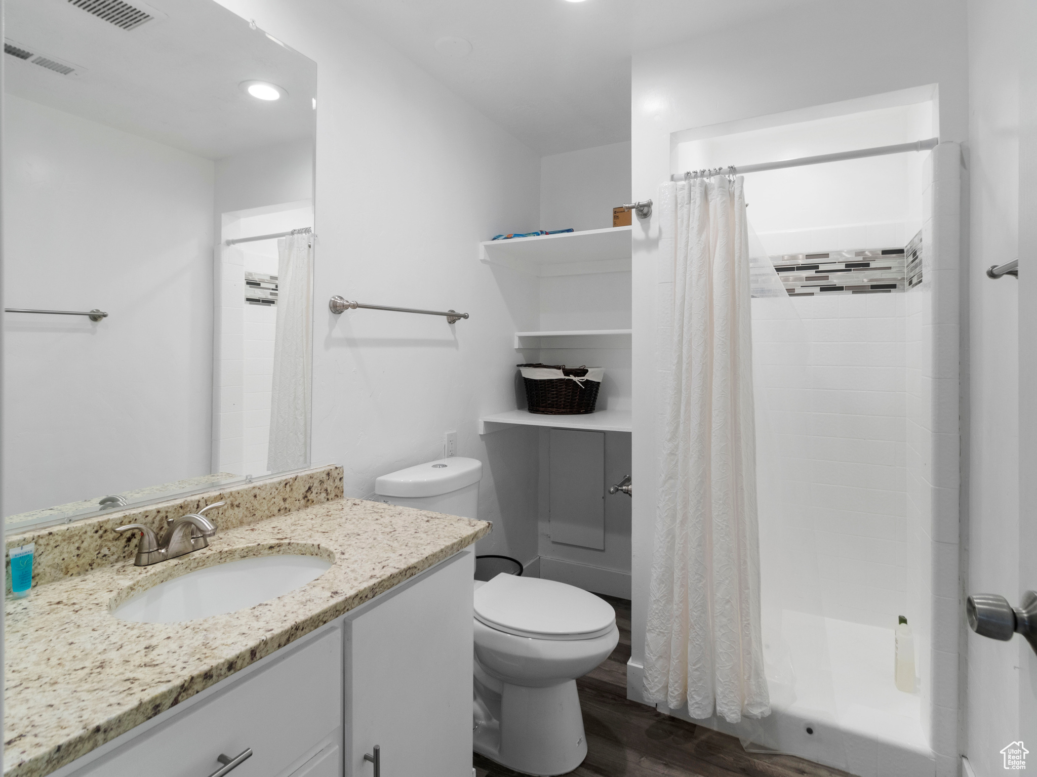 Full bathroom featuring hardwood / wood-style flooring, toilet, vanity, and shower / tub combo with curtain