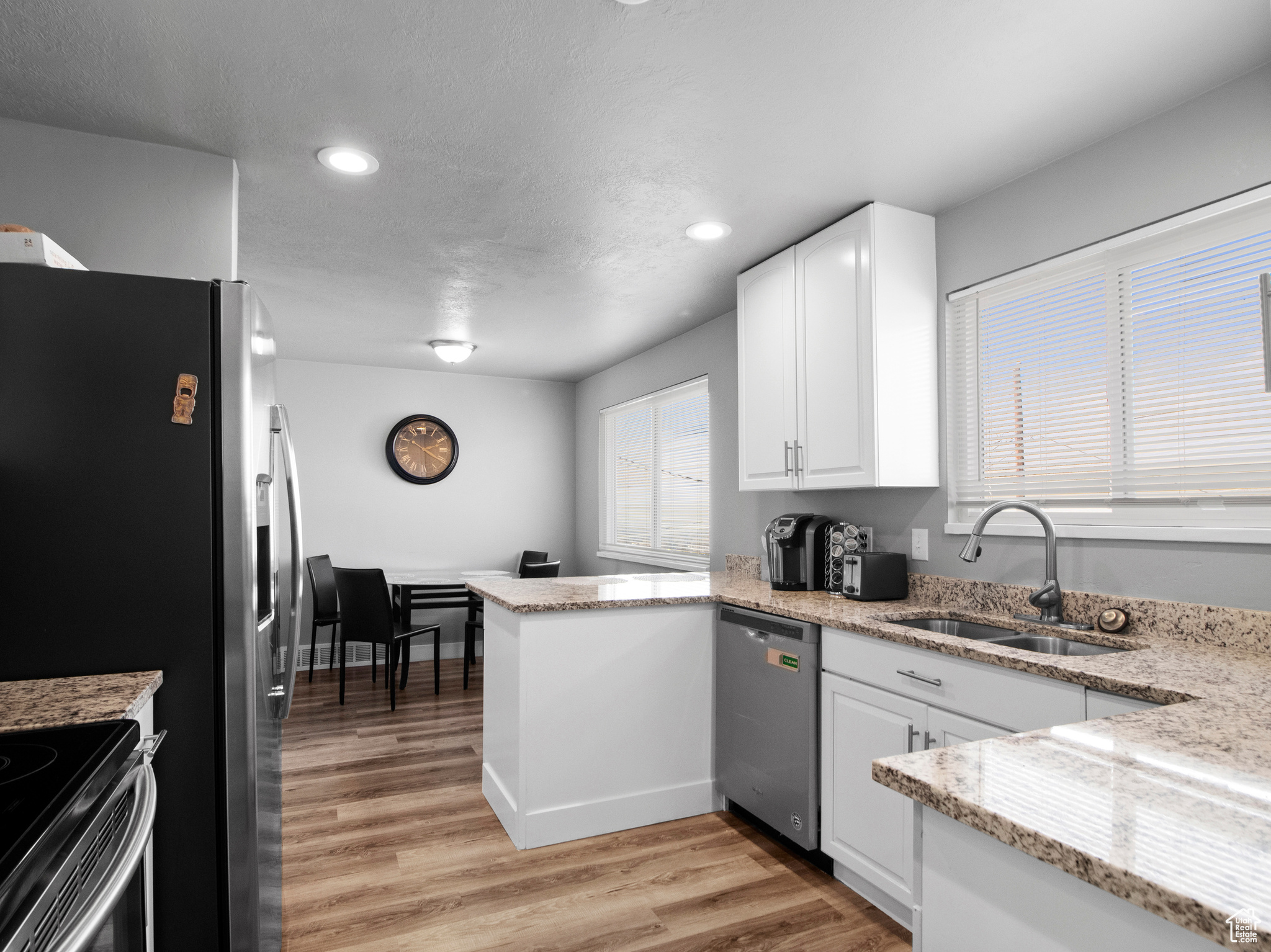 Kitchen with white cabinets, stainless steel appliances, light hardwood / wood-style floors, and sink