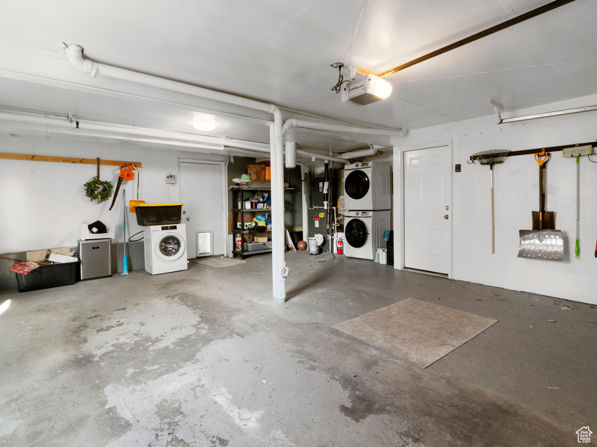 Garage featuring a garage door opener and stacked washer and dryer