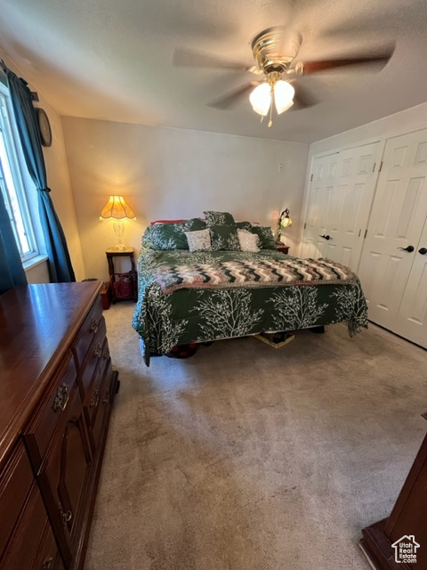 Carpeted master bedroom featuring ceiling fan and a closet