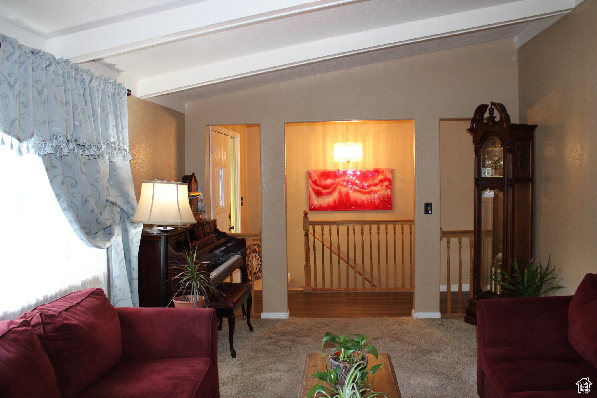 Living room featuring vaulted ceiling with beams and wood-type flooring.  Also view of front entrance.