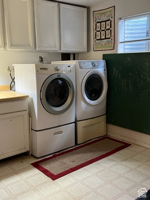 Laundry room featuring light patterned floors, washer and dryer, and cabinets.