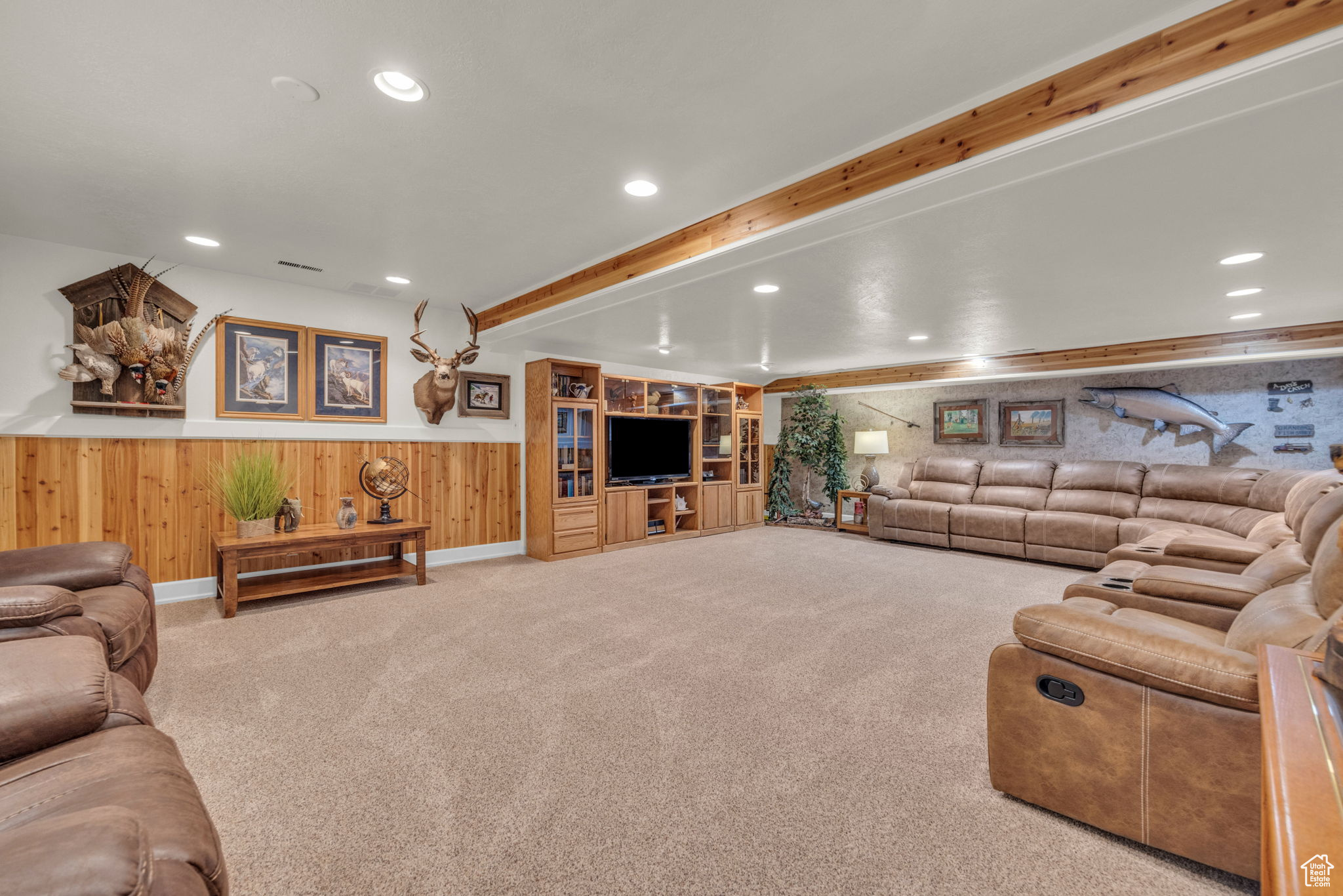 Basement living room with beam ceiling and light colored carpet