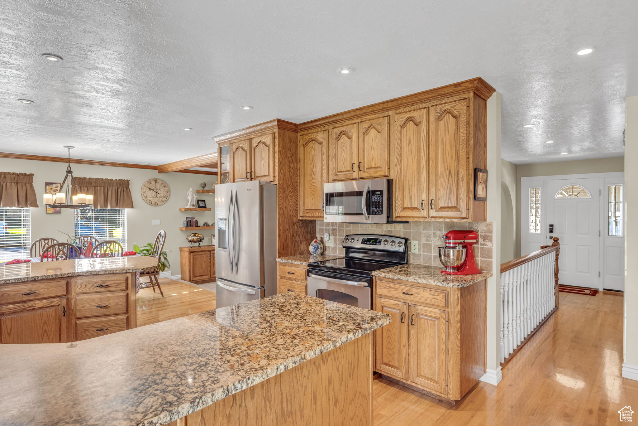 Kitchen featuring hanging light fixtures, tasteful backsplash, light wood-type flooring, and stainless steel appliances