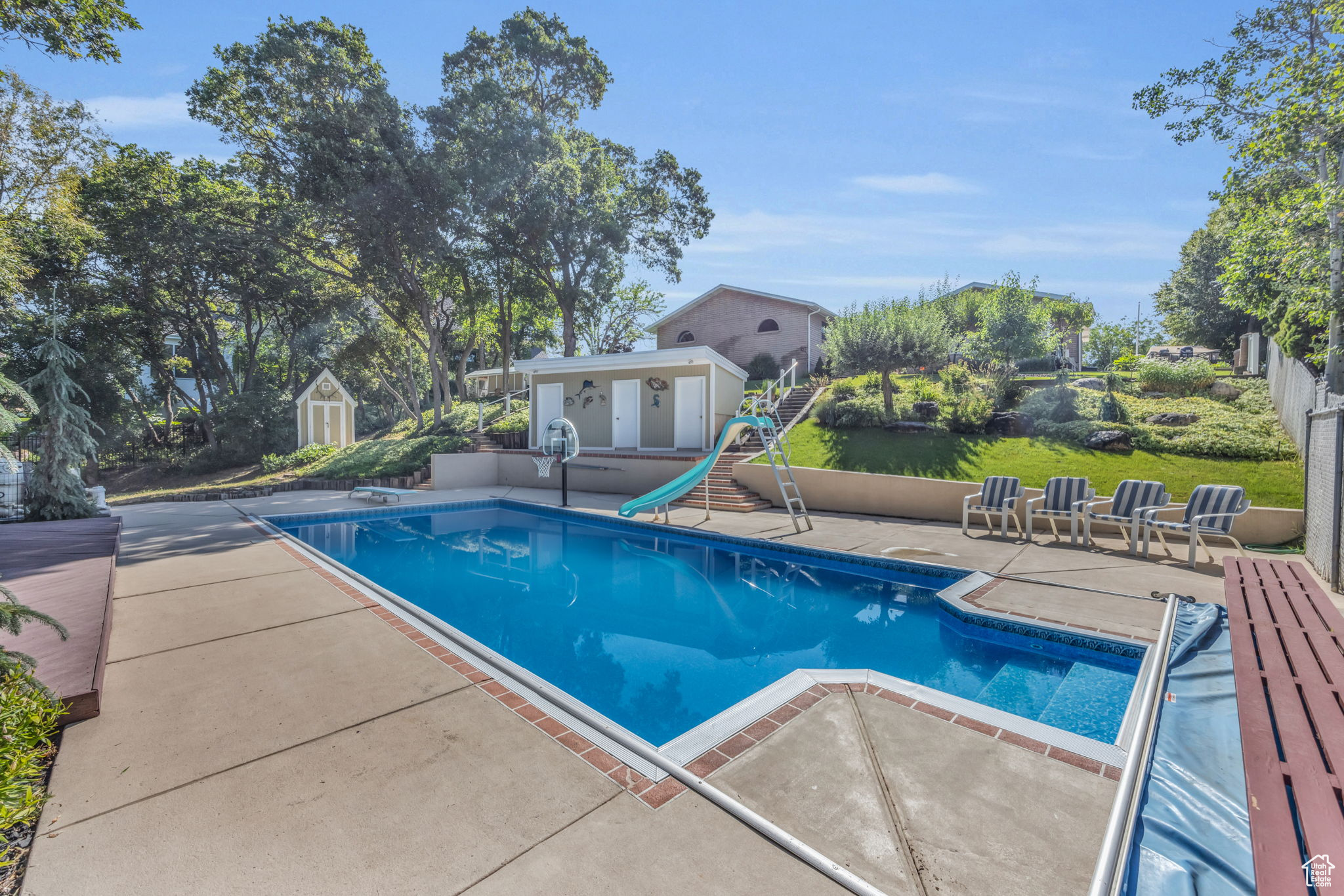 View of swimming pool featuring an outbuilding, a diving board, a patio area, and a water slide, and diving board