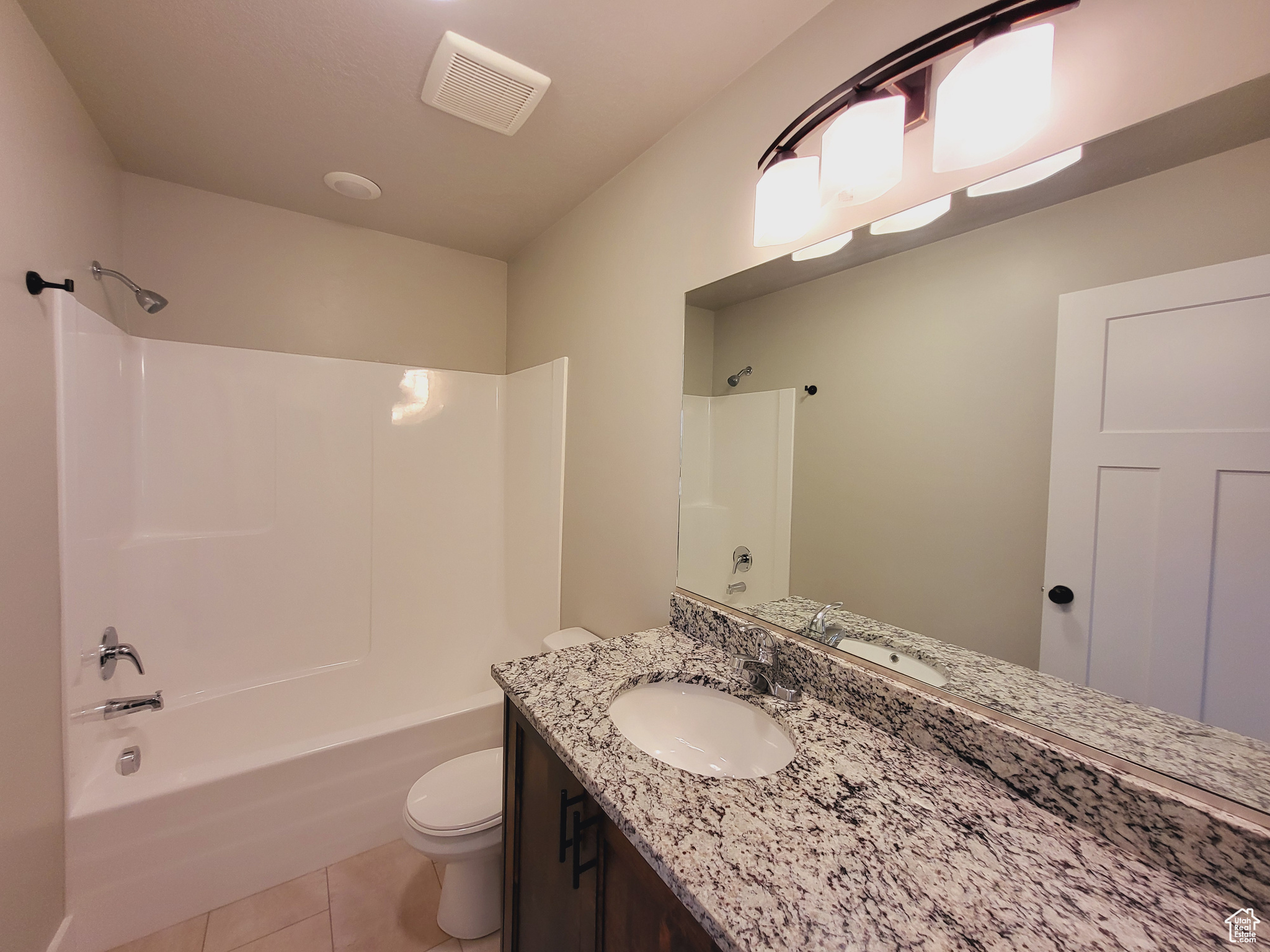 Full bathroom featuring tile patterned flooring, toilet, vanity, and shower / tub combination