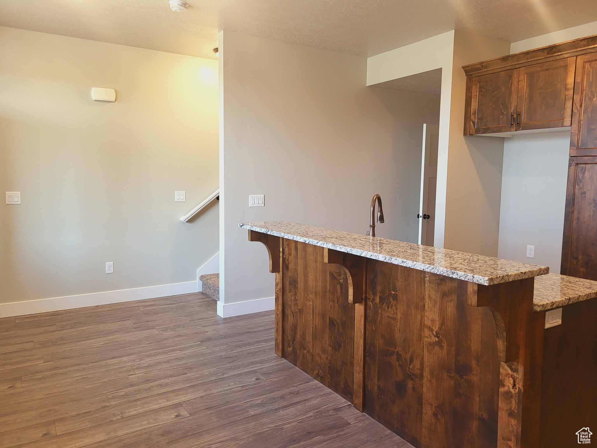 Kitchen featuring light stone countertops, hardwood / wood-style floors, and a breakfast bar