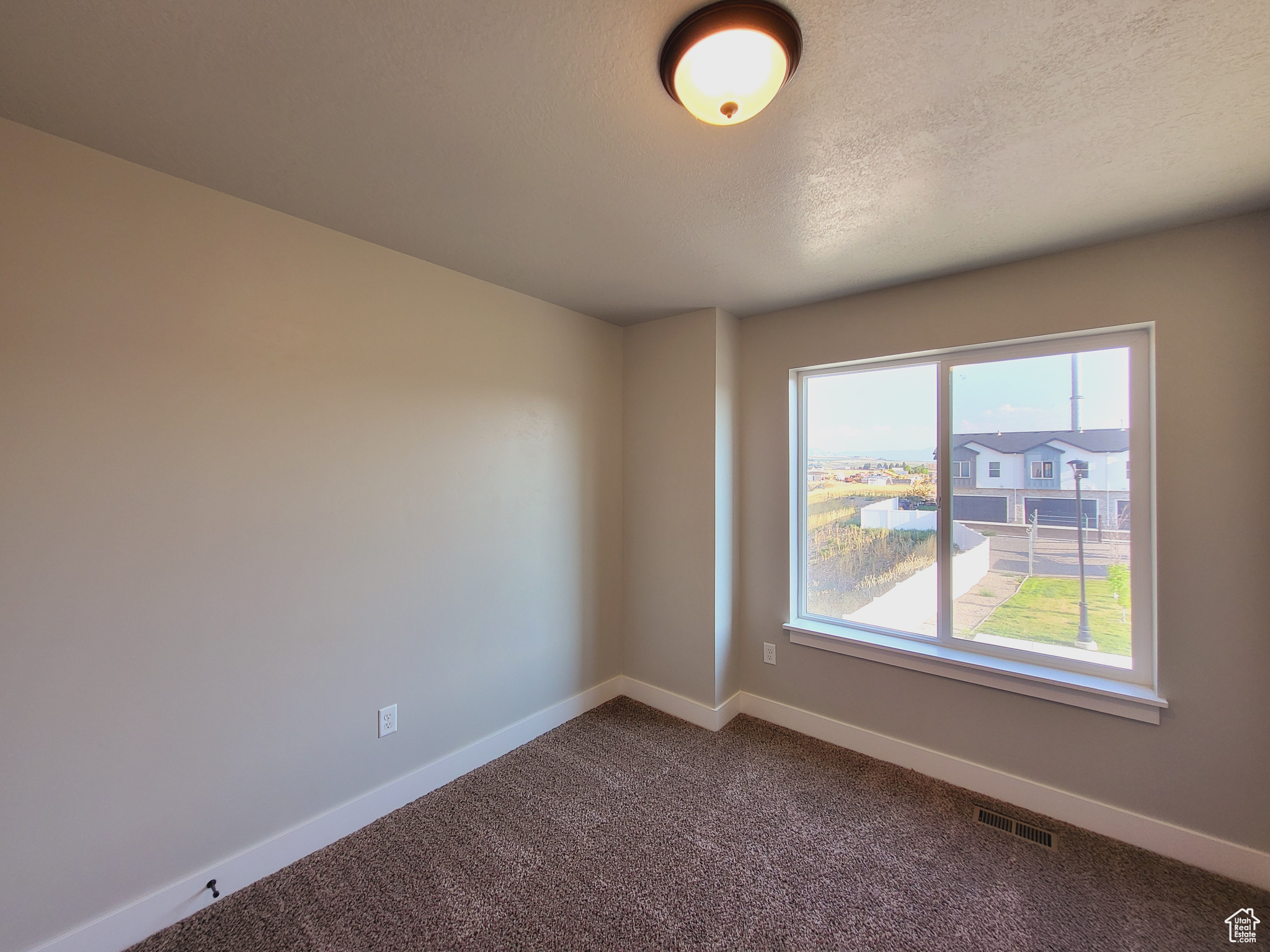 Unfurnished room with carpet and a textured ceiling