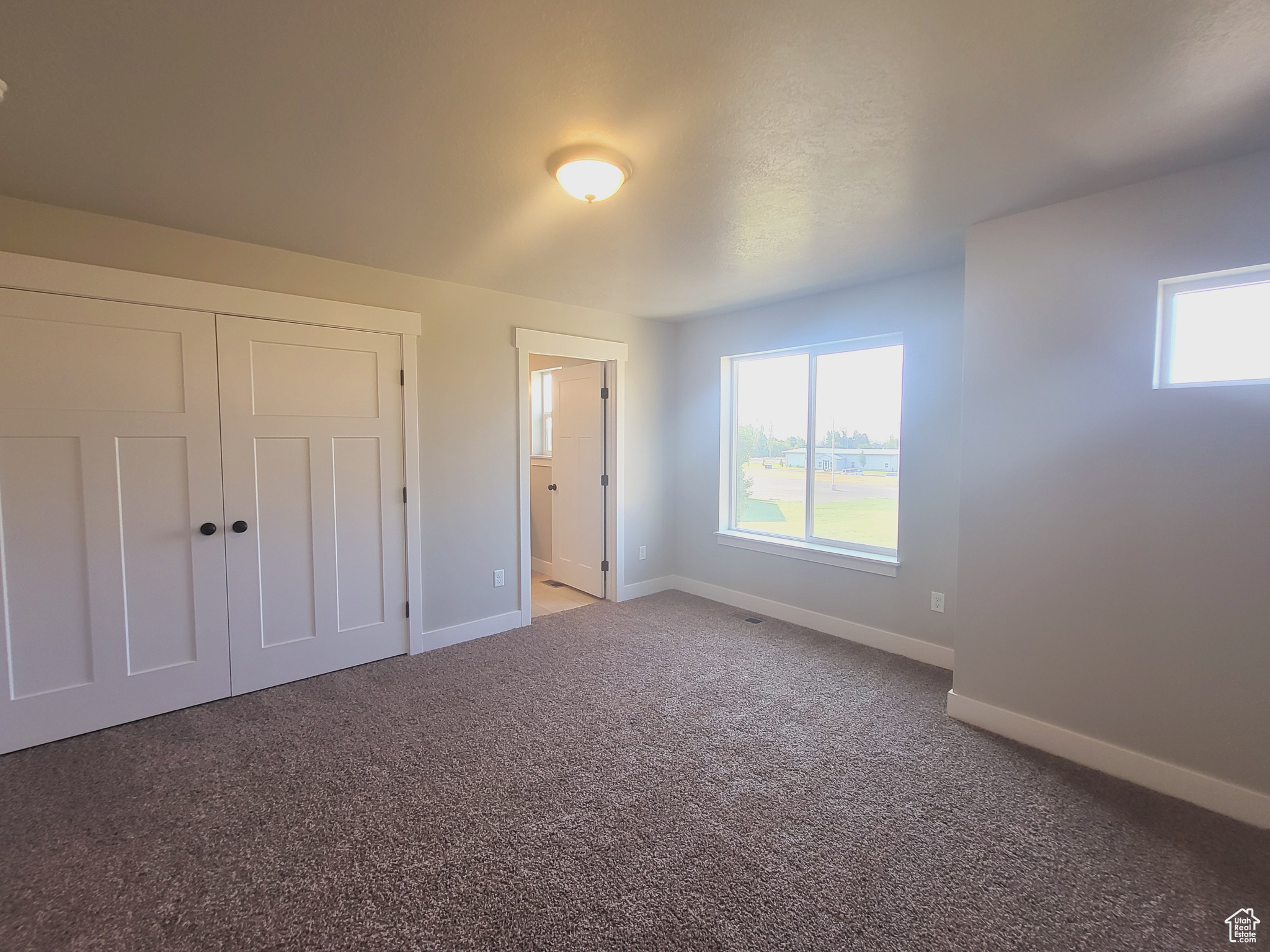 Unfurnished bedroom featuring a closet, connected bathroom, and light colored carpet