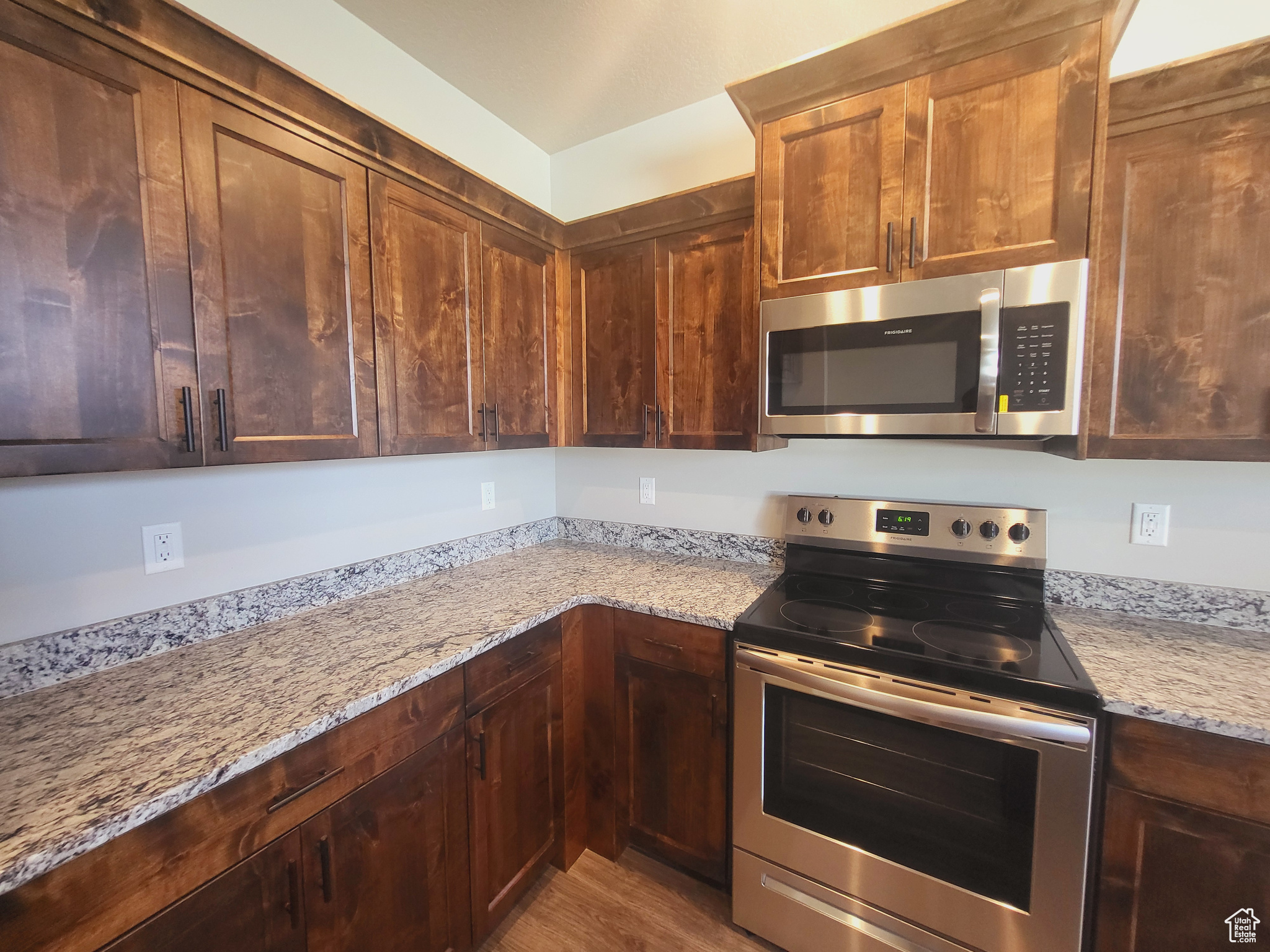 Kitchen featuring light stone counters, stainless steel appliances, and hardwood / wood-style floors