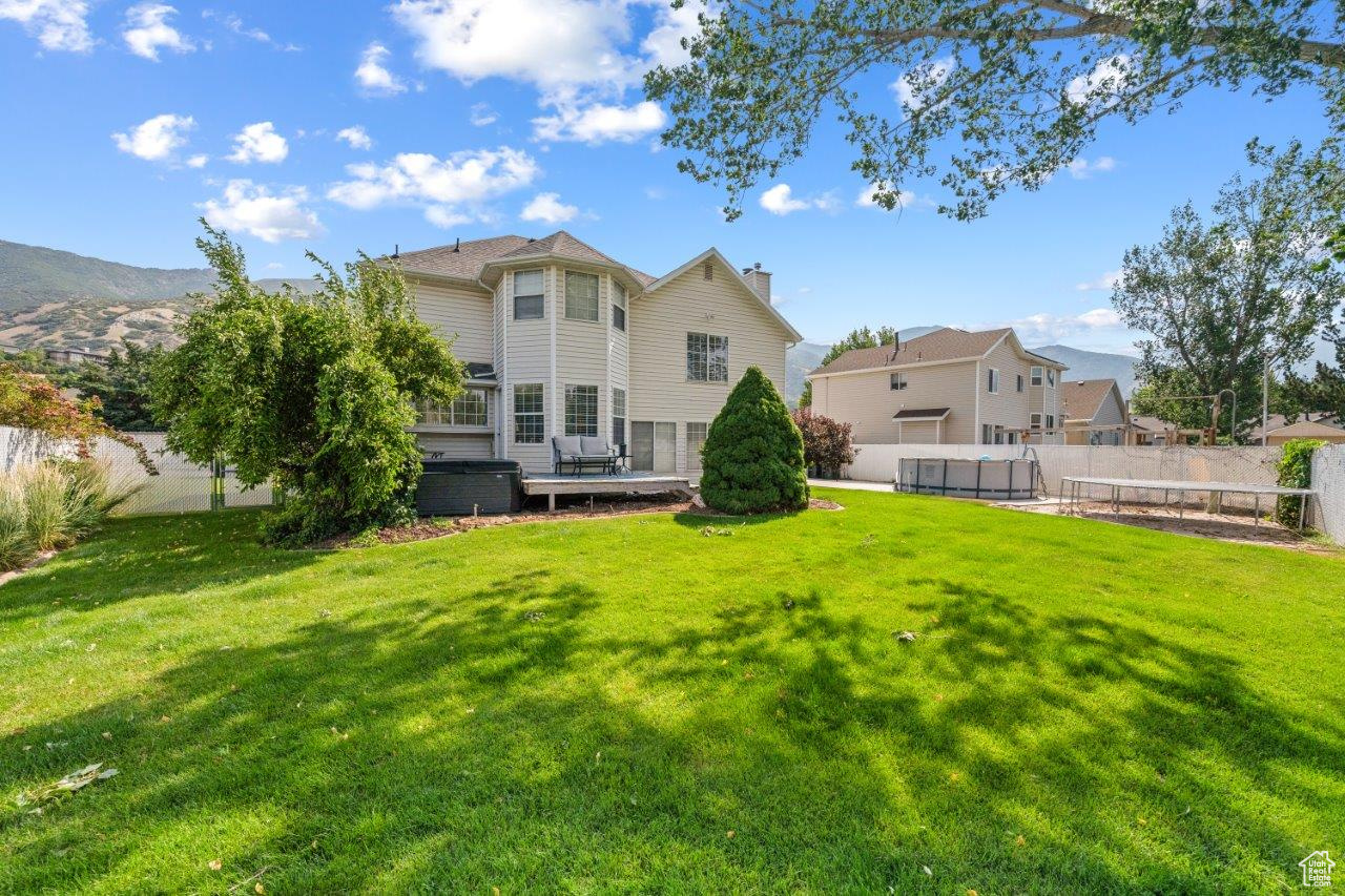 Back of house featuring a wooden deck and a lawn