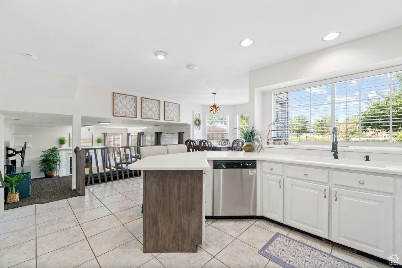 Kitchen featuring white cabinetry, light tile patterned floors, a kitchen island, stainless steel dishwasher, and sink