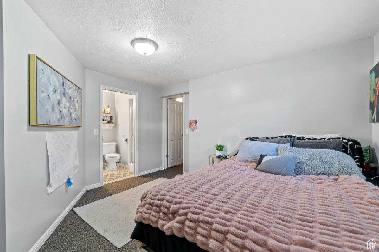 Bedroom featuring connected bathroom, carpet, and a textured ceiling