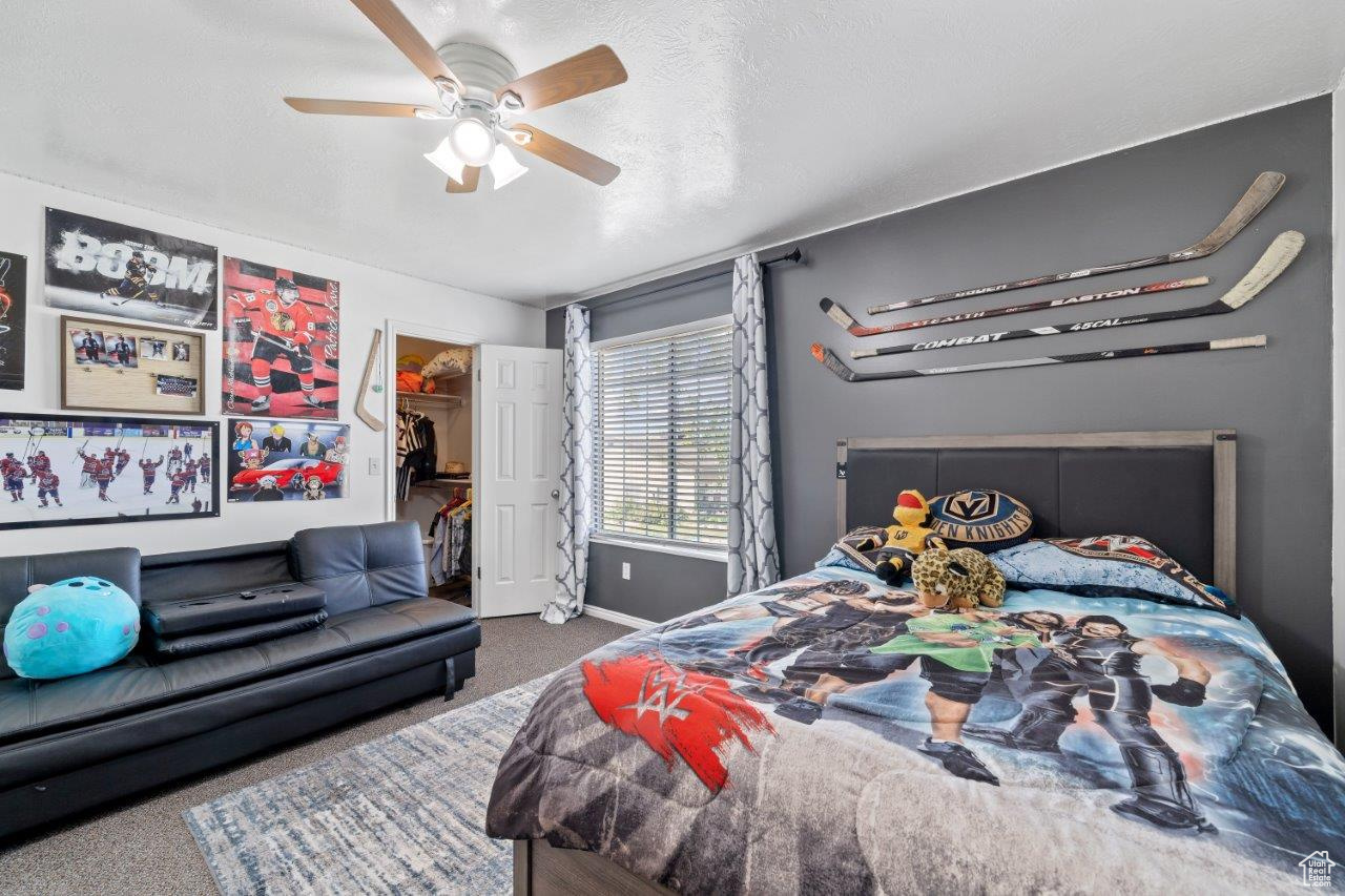 Carpeted bedroom featuring a closet, ceiling fan, and a walk in closet