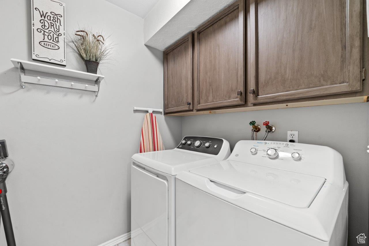 Laundry area with washer and clothes dryer and cabinets