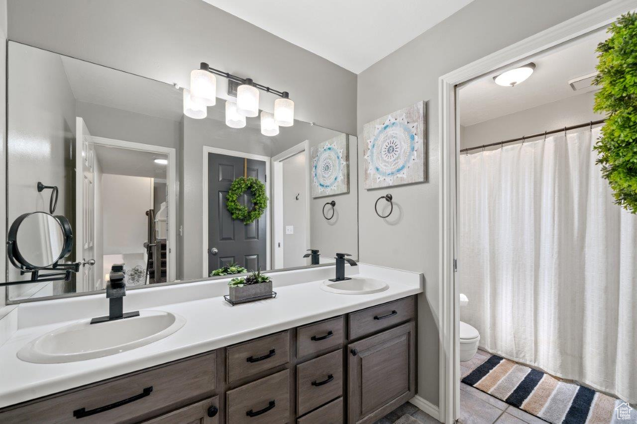 Bathroom with dual vanity, toilet, and tile patterned floors