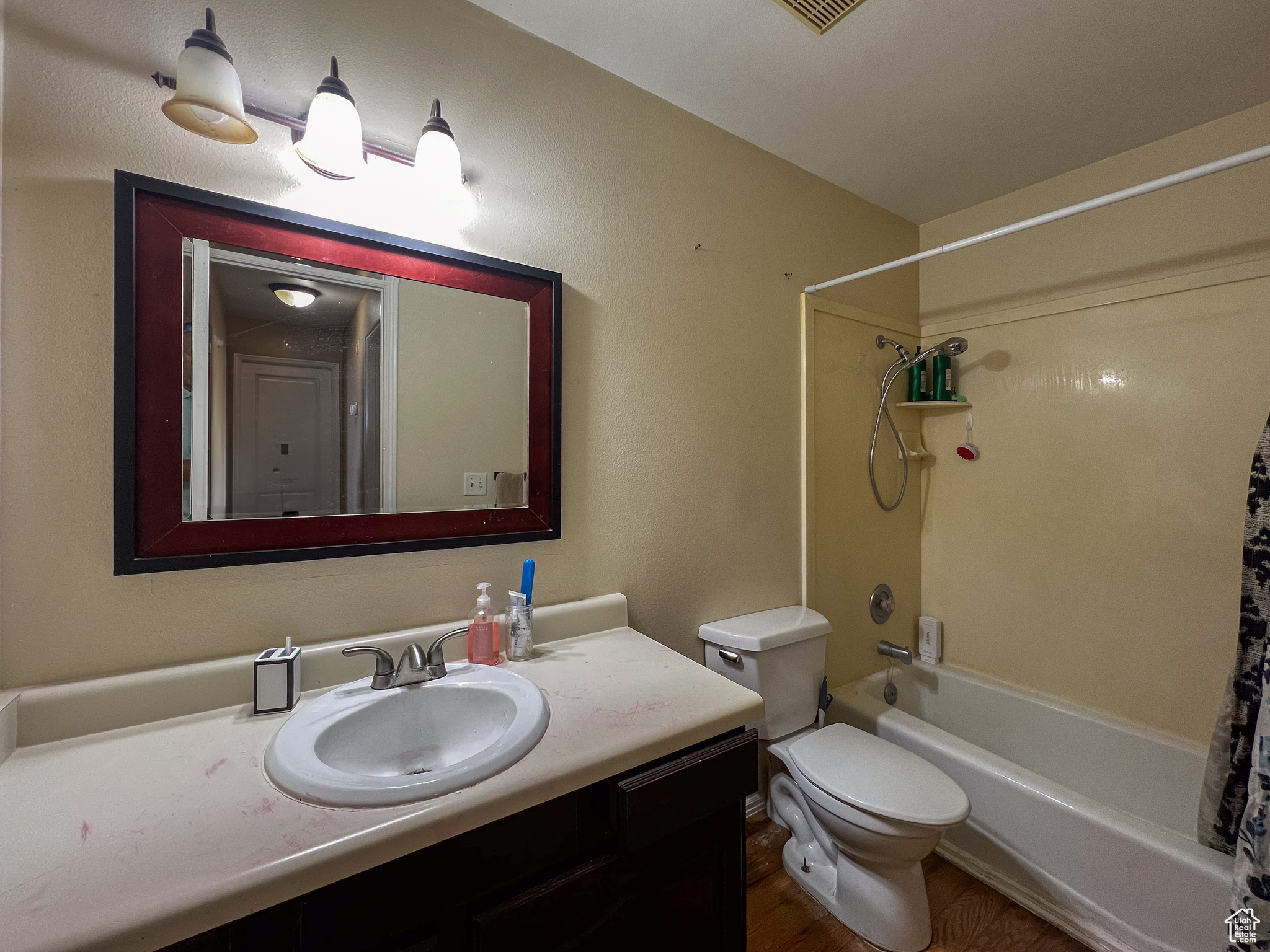 Full bathroom with shower / tub combo, wood-type flooring, toilet, and vanity