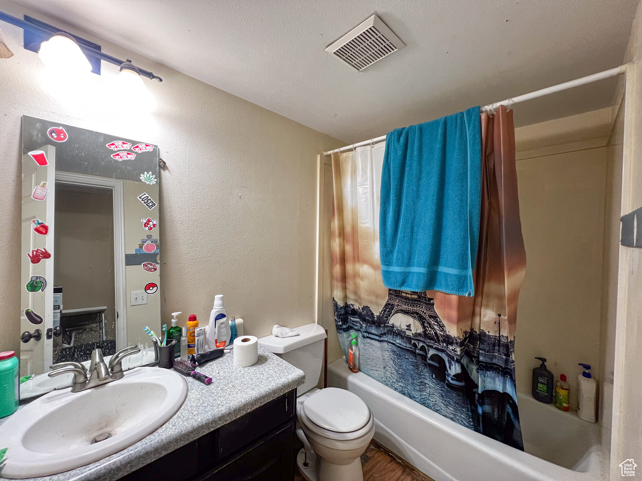 Full bathroom with vanity, shower / bath combo, and toilet