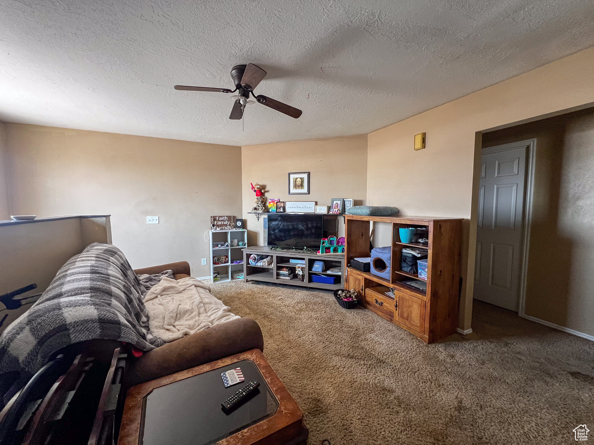 Carpeted living room with a textured ceiling and ceiling fan